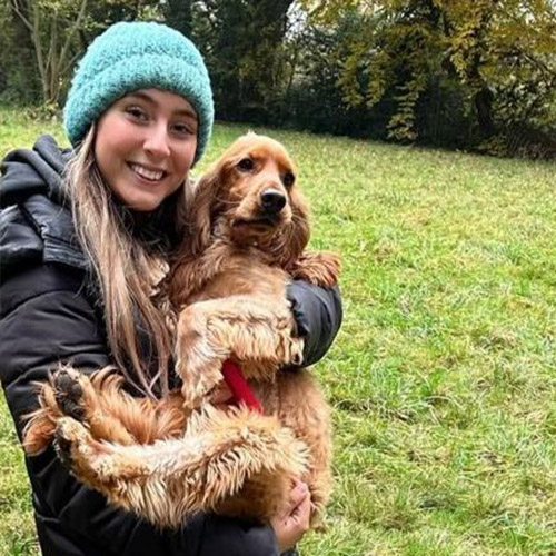 Regan holding a dog in a field.