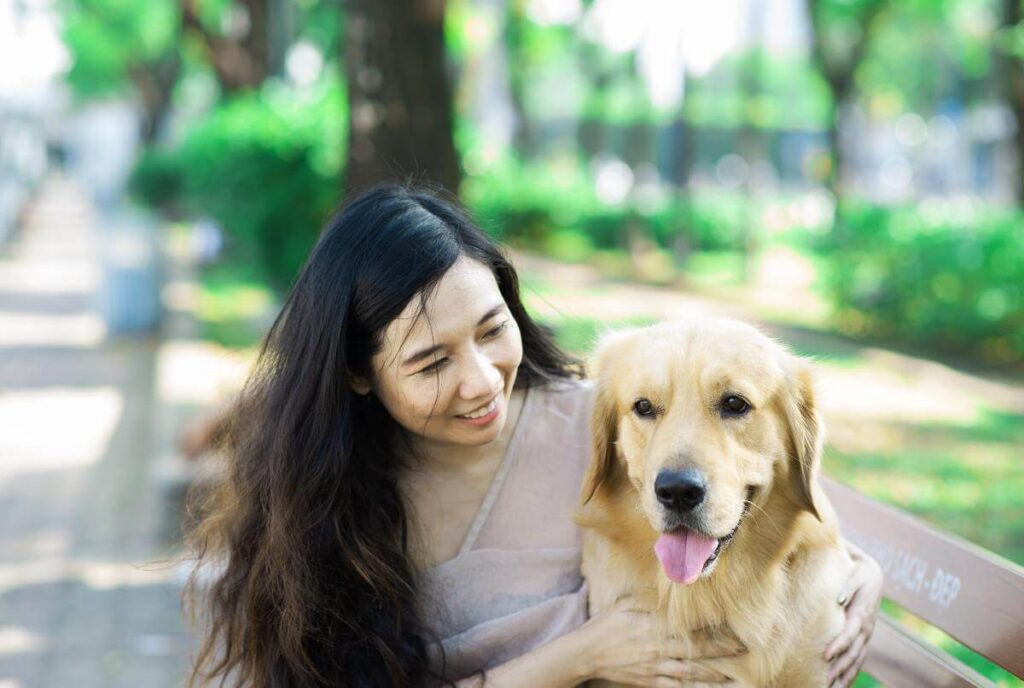 A woman is sitting on a bench with her dog